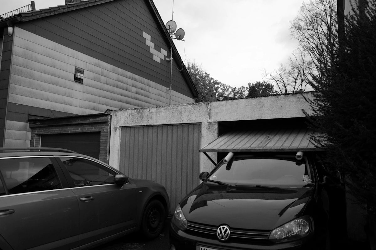 Two cars parked in front of a row of small garages