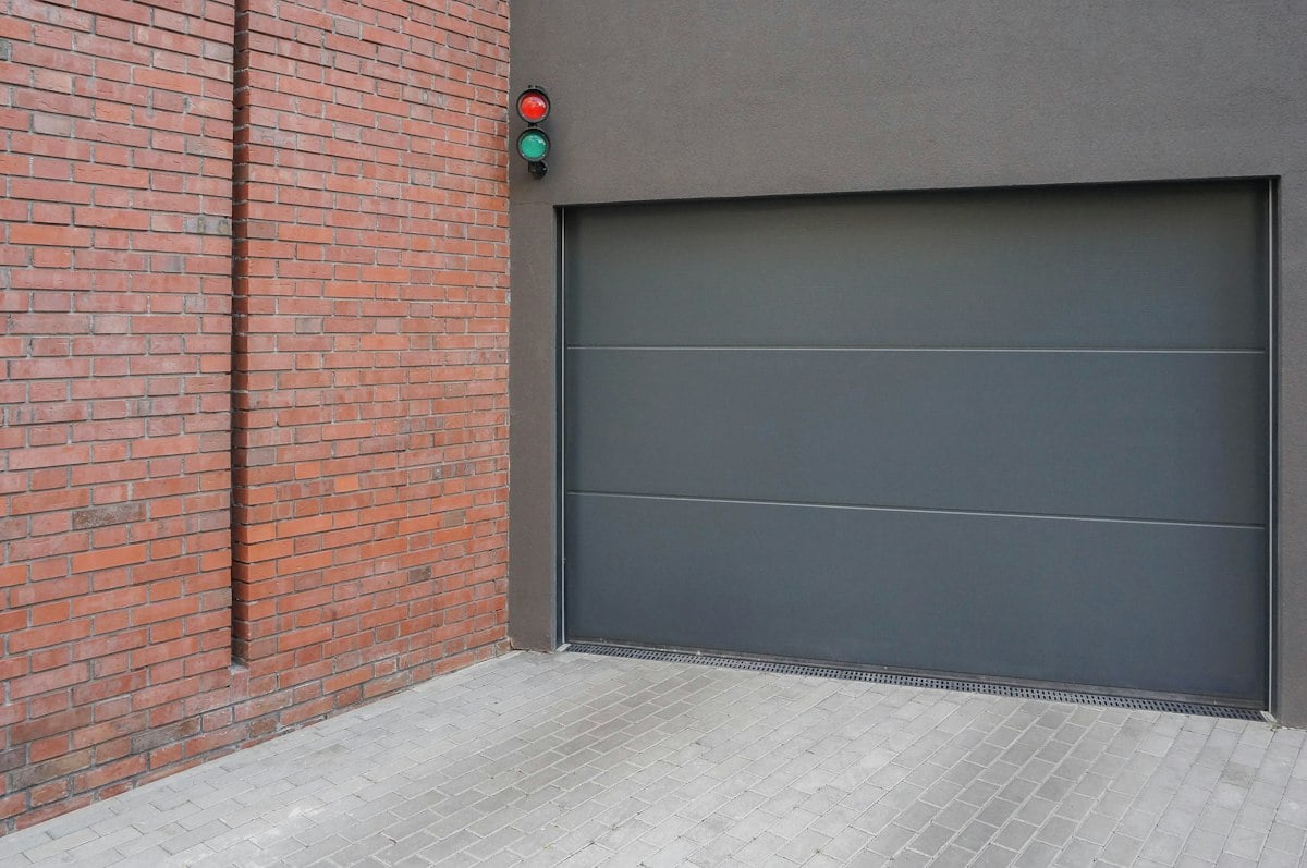 Gray sectional garage door set into a brick wall