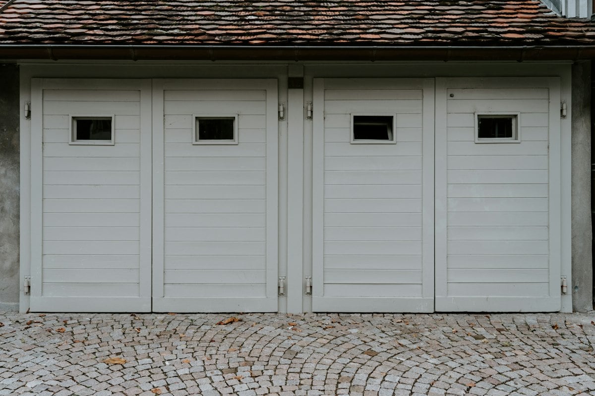 Four white side-hinged garage doors with small windows